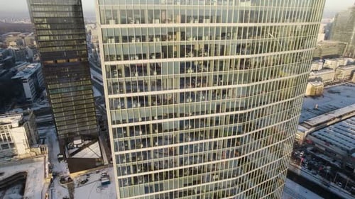 Aerial fast descending shot of a modern office building in the business district during the pandemic