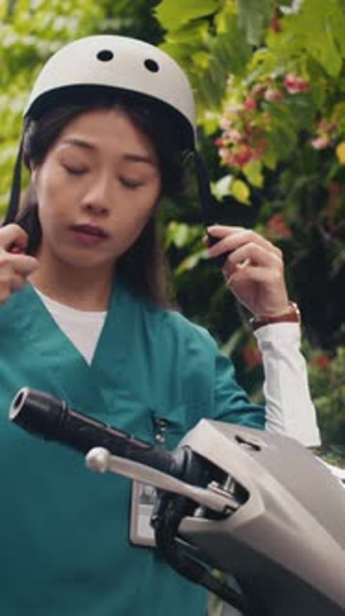 Woman in Scrubs Putting on Motorcycle Helmet