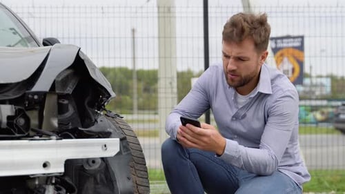 Man On Phone Next To Wrecked Car