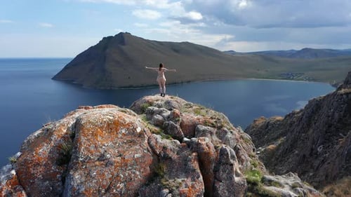 Young Woman in Short Dress Running Up on Top of Mountain Above the Sea