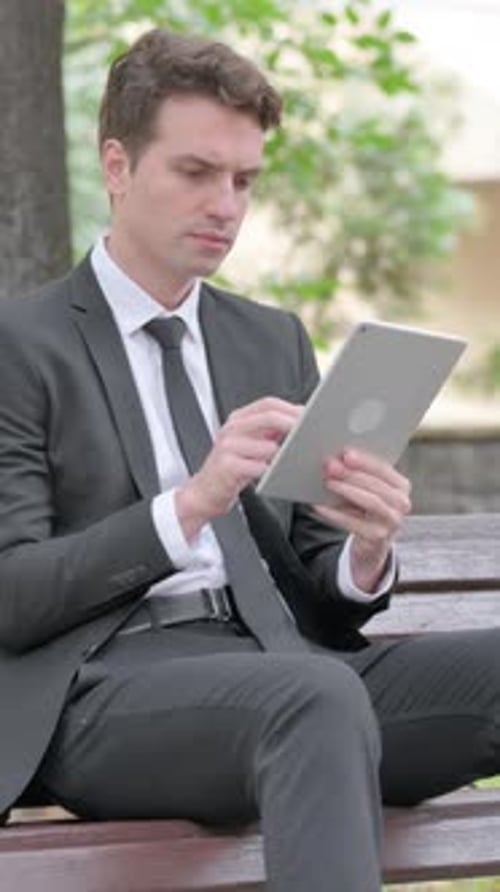 Young Businessman using Tablet while Sitting Outdoor on a Bench, Vertical Video