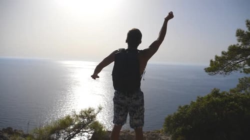 Man Celebrates Ocean View Success on Cliff Top