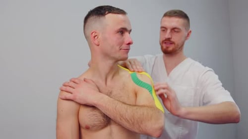 Applying Kinesiology Tape to a Patient's Shoulder