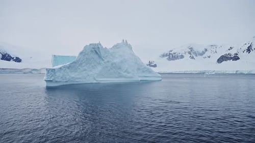 Massive Floating Iceberg Drift Through The Serene Frozen Antarctic Waters