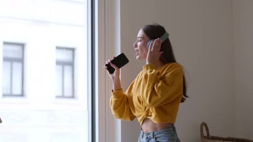 Woman Sings and Dances with Headphones and Cellphone