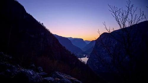 Timelapse shot of mountain slope in Norwegian Fjord in Flam, Norway getting dark at dusk.