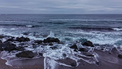 Waves crash on rocky shore during cloudy day in coastal area