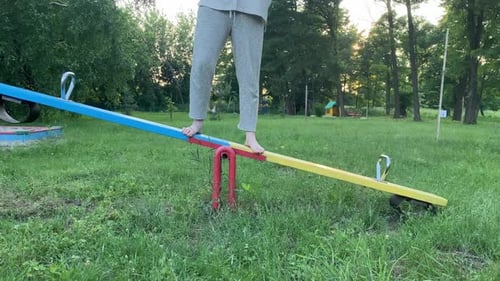 Barefoot Female Person Finds Equilibrium on Playground Outdoors