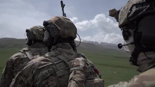 Soldiers in Camouflage Gear Standing on Green Hillside