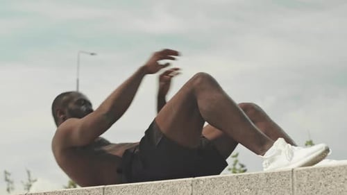 Afroamerikaner ohne Hemd, der draußen Crunches macht