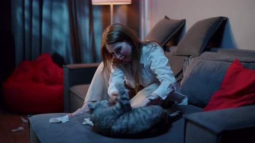 Woman Plays with her Cat on Gray Sofa