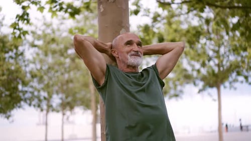 Senior Man Relaxing Against Tree in Urban Park