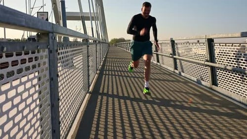 Male runner running on the bridge in the city during day.
