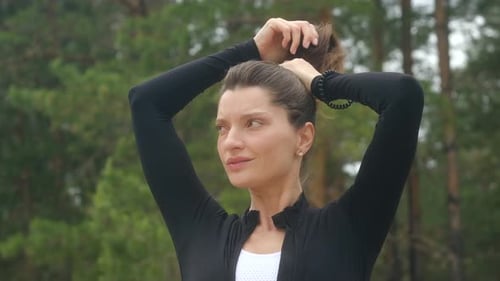 Woman Ties Up Hair for Exercise in Forest