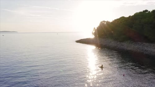 Aerial view of woman doing paddle surf in the mediterranean coast with a low sun