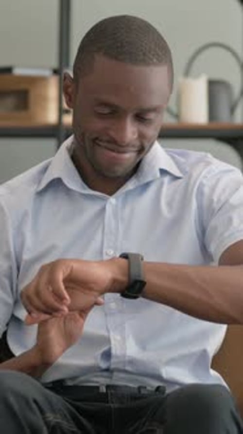 Vertical Video of African Man Using Smart Watch while Sitting Outdoor on Bench