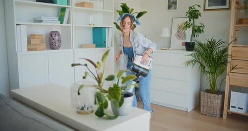 Cheerful Woman Dances While Vacuuming Apartment
