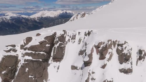 Extreme freeride Snowborder on summit of mountain speeding down steep snowy mountain in sunlight. Da