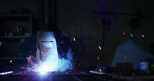 .A blacksmith or welder, with his welder, welding steel and iron, in extreme slow motion. The weld