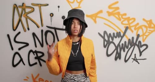 Stylish woman dancing in front of graffiti art