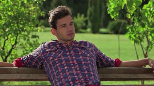 Relaxed Male Student Enjoying a Sunny Day on a Park Bench