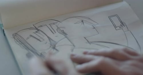 Hand drawing figures in sketchbook with pencil