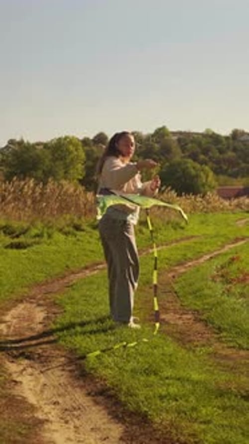 Woman Flies Kite in Grassy Rural Field