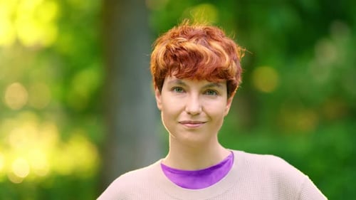 Smiling Nonbinary Person Looking at the Camera Outdoors
