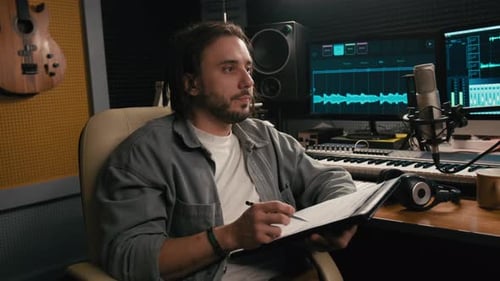 Young Male Podcast Presenter Writing Interview Plan in Studio
