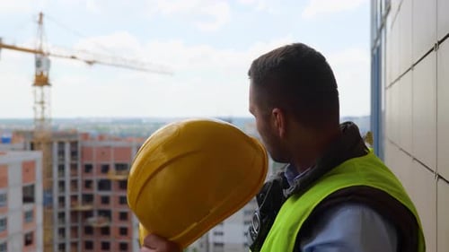 Tired Male Architect Taking Off His Helmet While Standing on the Roof of Building Construction in