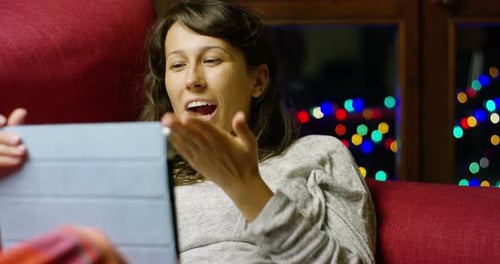 A girl from the couch of his home greets you with its tablet in video call her boyfriend because n