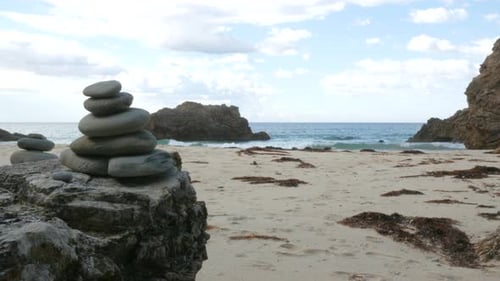 Handaufnahme eines meditativen Felsstapels mit Meer und Wellen im Hintergrund