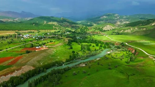 A large, lush green field with a dirt road running through it