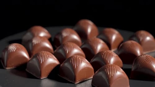 Delicious Assorted Milk Chocolates Rotating on Dark Background