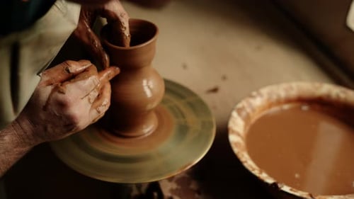 Unrecognized clay artist modeling wet clay jar in pottery workshop studio slow motion