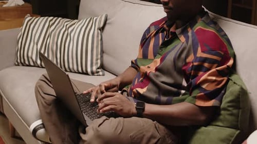Man Typing on Laptop Computer at Home