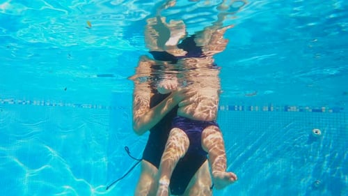Underwater Shot of Swim Instructor Guiding Six Month Old Baby Boy Through Infant Swimming Exercises