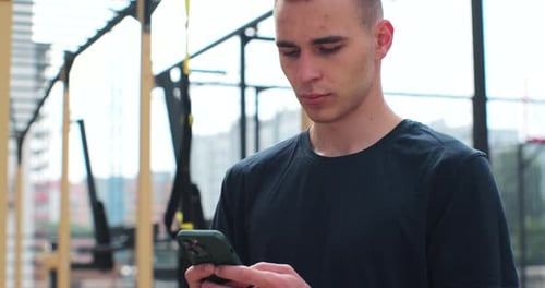 Close Up of Man Using Smartphone Checking Fitness Applications Standing at Sport Ground Healthy