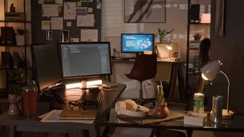 Computerbildschirme, auf denen nachts Code im leeren Programmierbüro angezeigt wird