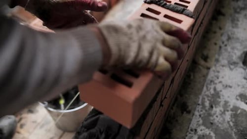 Construction Worker Laying Hollow Brick on Mortar