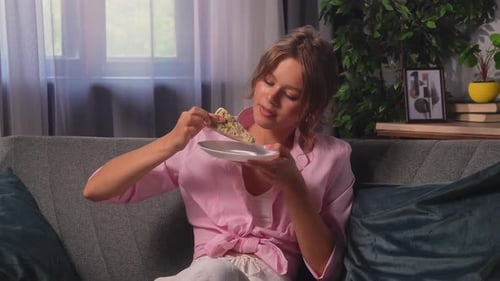 Young Woman Eating Slice of Cake on Sofa