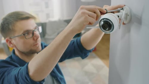 Man Installs Wireless Security Camera on Home Wall