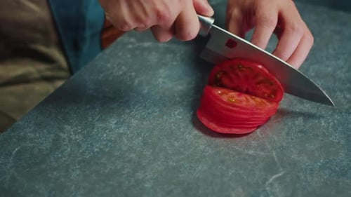 the Chef Cuts the Tomato Into Slices with a Sharp Knife a Close Up View