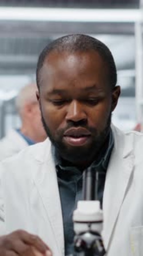Man Examining Sample With Microscope in a Lab
