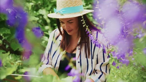 Femme au chapeau de paille appréciant la nature tout en peignant entourée de fleurs violettes vibrantes