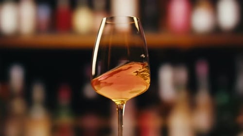 Orange or White Rose Wine Bottle and Glass Against a Sunset in a Peaceful Vineyard Pouring of