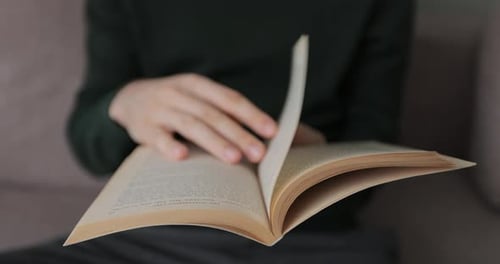 Man is Lifestyle Sitting on Couch in Cozy Room Reading Favorite Book