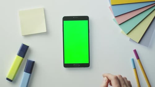O designer está usando um telefone Android com tela verde no modo retrato. Vista superior.