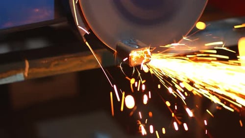 Angle grinder with massive disk cutting through metal with many sparks, handheld view