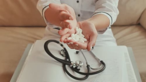 Doctor Displaying White Pills in Hands at Home